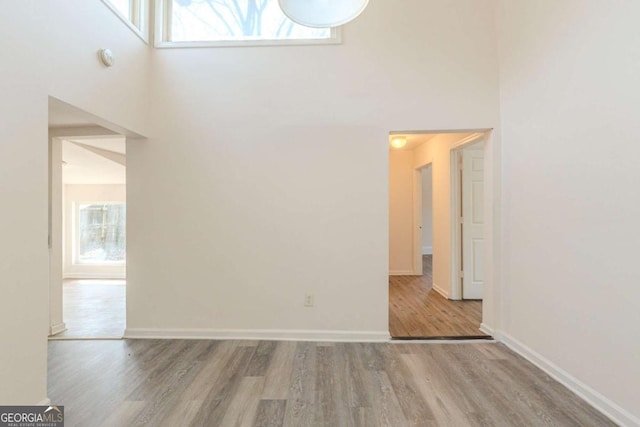 interior space with a high ceiling, wood finished floors, and baseboards