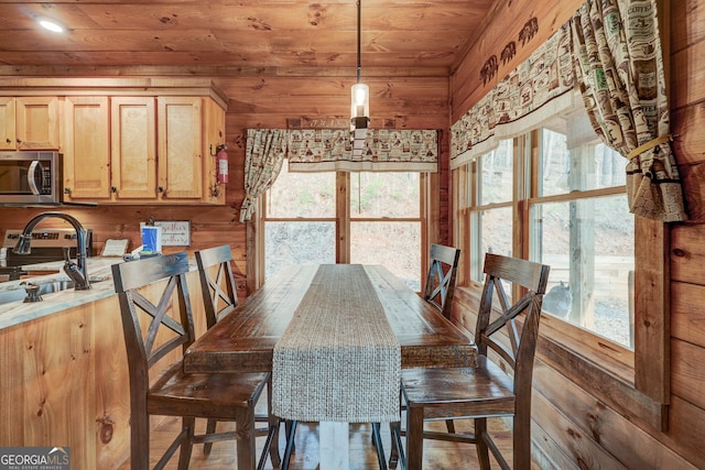 dining space with a wealth of natural light, wooden walls, and wood ceiling