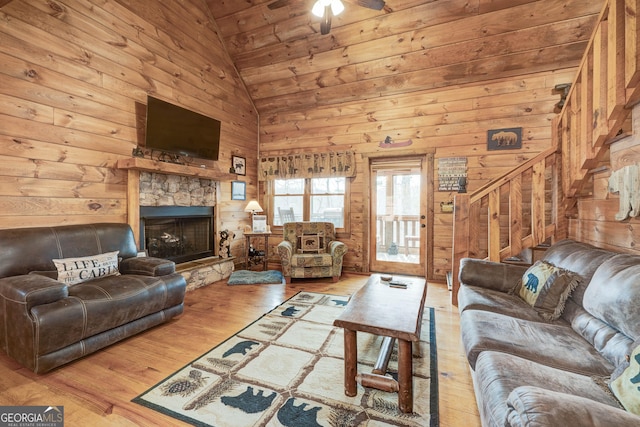 living room with lofted ceiling, wood-type flooring, wood walls, wood ceiling, and stairs