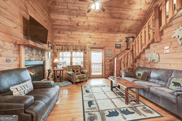 living room featuring wooden walls, vaulted ceiling, wood-type flooring, wooden ceiling, and a stone fireplace