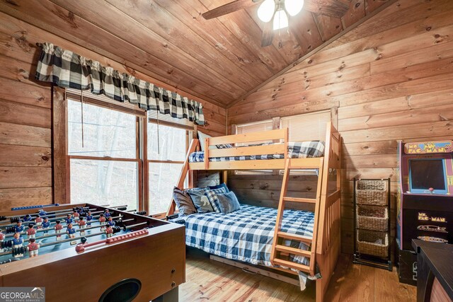 bedroom featuring vaulted ceiling, wood finished floors, wood ceiling, and wooden walls