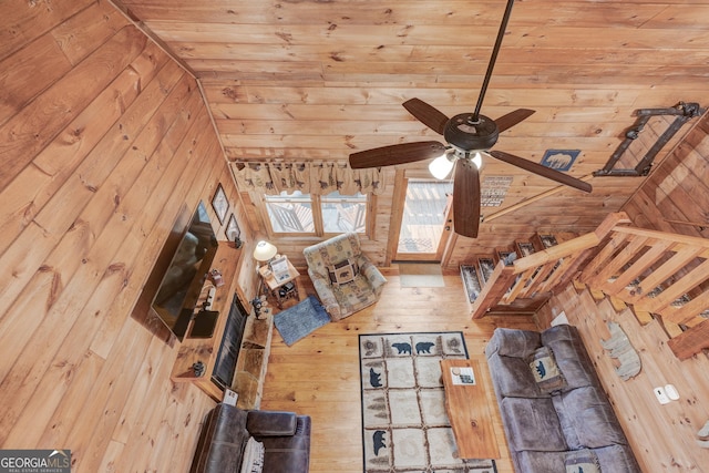 unfurnished living room with wood walls, wooden ceiling, and ceiling fan