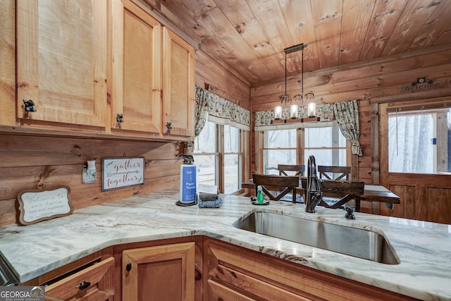 kitchen featuring a wealth of natural light, a sink, wooden walls, an inviting chandelier, and wooden ceiling