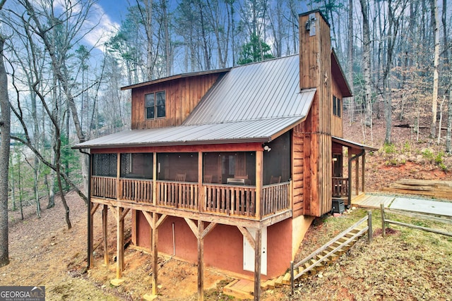 view of outdoor structure featuring a sunroom and a forest view