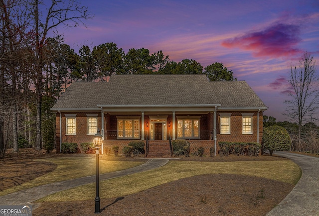 view of front facade with brick siding, a porch, and a front lawn