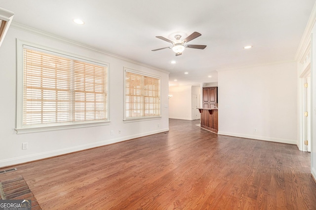 unfurnished living room with crown molding, wood finished floors, a ceiling fan, and visible vents