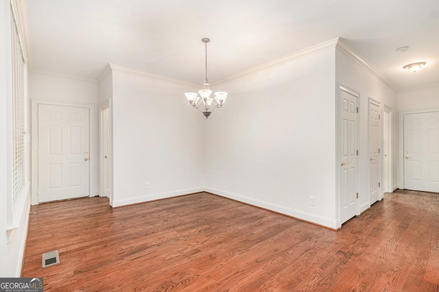 unfurnished dining area with visible vents, wood finished floors, an inviting chandelier, crown molding, and baseboards