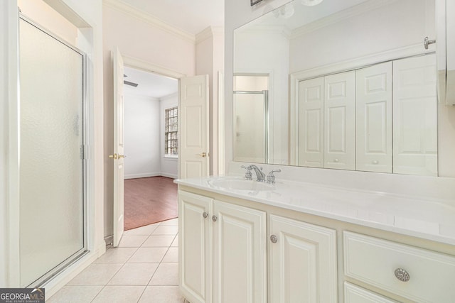 bathroom featuring ornamental molding, a shower stall, tile patterned flooring, baseboards, and vanity