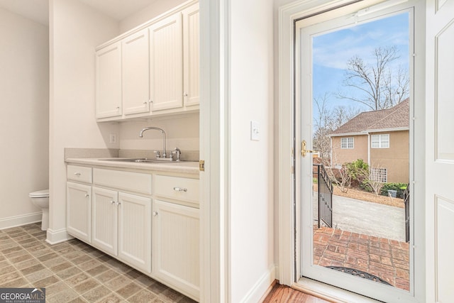 clothes washing area with baseboards and a sink