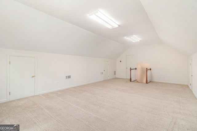 additional living space featuring visible vents, light colored carpet, baseboards, and lofted ceiling