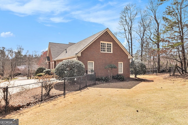 view of side of property with fence, brick siding, and a lawn