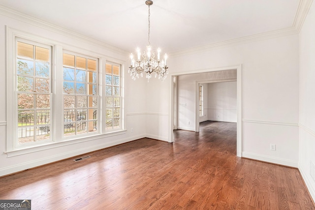 unfurnished dining area featuring wood finished floors, visible vents, baseboards, an inviting chandelier, and crown molding