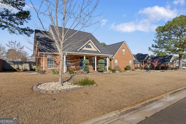 view of front of home featuring a front yard, fence, and brick siding