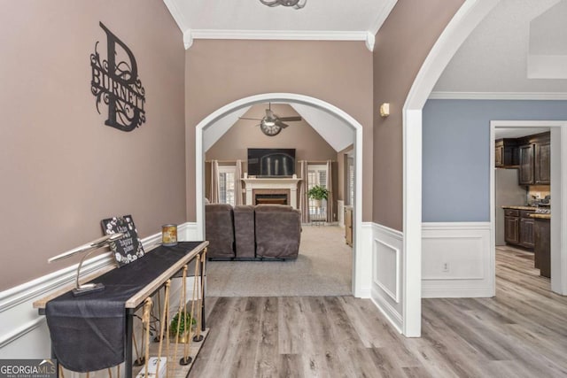 foyer featuring arched walkways, ceiling fan, wainscoting, and ornamental molding