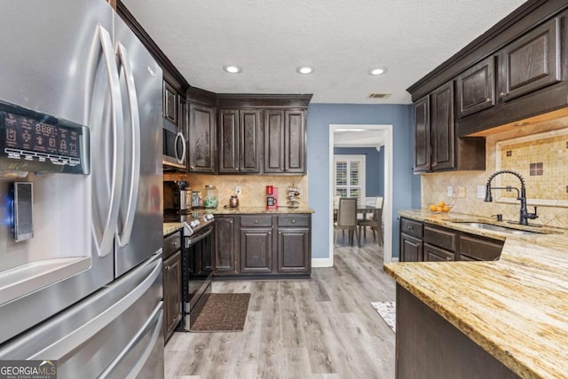 kitchen with visible vents, dark brown cabinets, stainless steel appliances, and a sink