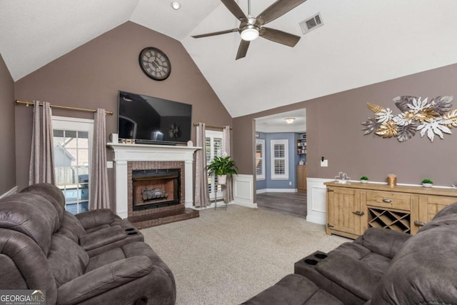 living room with a ceiling fan, visible vents, high vaulted ceiling, light carpet, and a brick fireplace