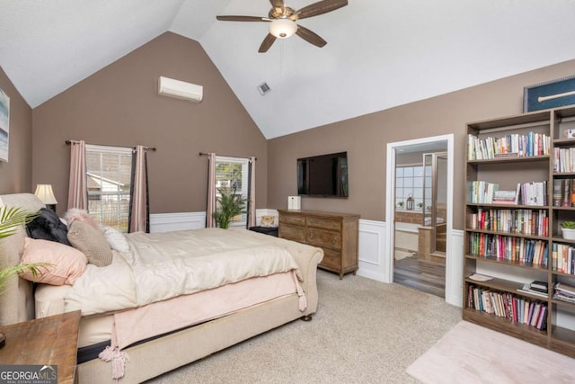 carpeted bedroom with a wall unit AC, visible vents, high vaulted ceiling, wainscoting, and connected bathroom