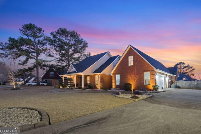 view of front of home featuring a garage, brick siding, concrete driveway, and fence