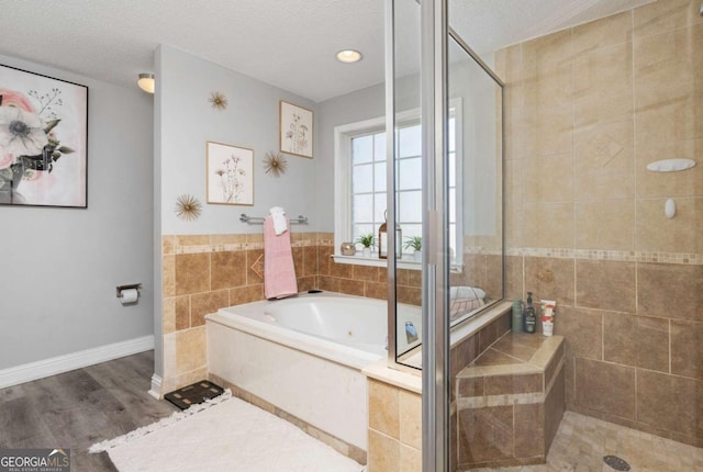 bathroom with baseboards, a tub with jets, a stall shower, and a textured ceiling