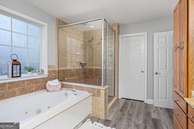 full bath featuring a bath, a shower stall, a textured ceiling, and wood finished floors