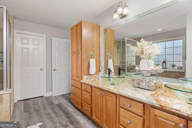 bathroom with vanity, wood finished floors, a stall shower, and a textured ceiling