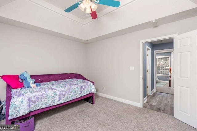 bedroom featuring a raised ceiling, carpet flooring, a ceiling fan, and baseboards