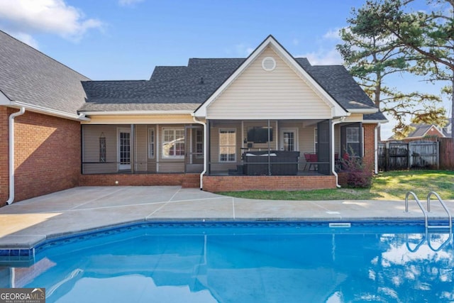 back of property featuring a patio, fence, a fenced in pool, a shingled roof, and brick siding