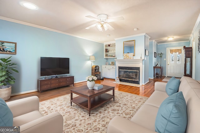 living room featuring crown molding, wood finished floors, baseboards, and ceiling fan