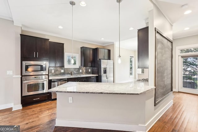 1199 Huff Rd Unit 121, Atlanta, GA 30318 - kitchen featuring appliances with stainless steel finishes, wood finished floors, decorative backsplash, a peninsula, and crown molding