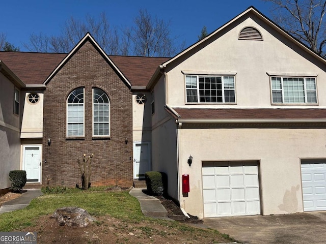 view of front of house with stucco siding, brick siding, and an attached garage