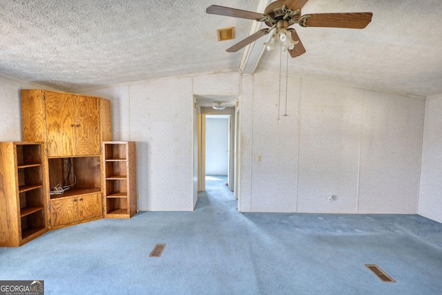 unfurnished living room with ceiling fan, carpet flooring, visible vents, and a textured ceiling