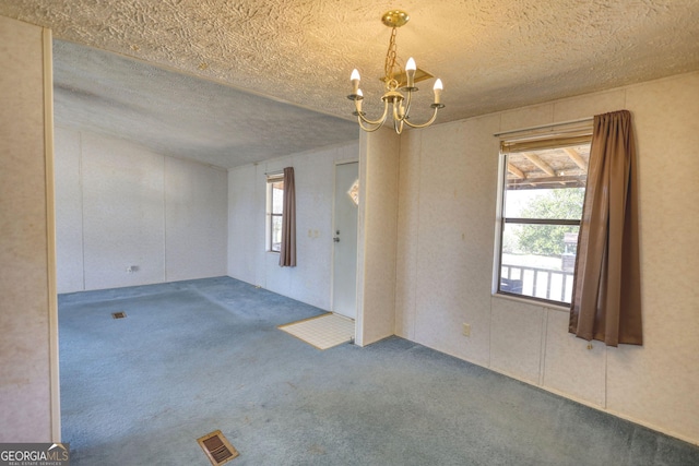 carpeted spare room featuring a chandelier, visible vents, and a textured ceiling