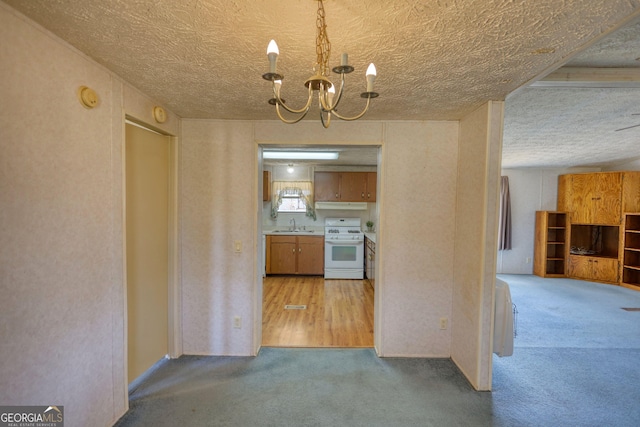 kitchen with white gas range, a notable chandelier, under cabinet range hood, and carpet floors