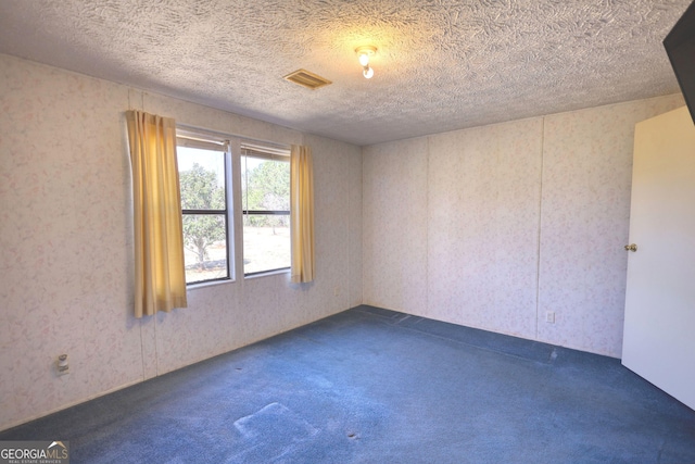 carpeted spare room with visible vents, wallpapered walls, and a textured ceiling