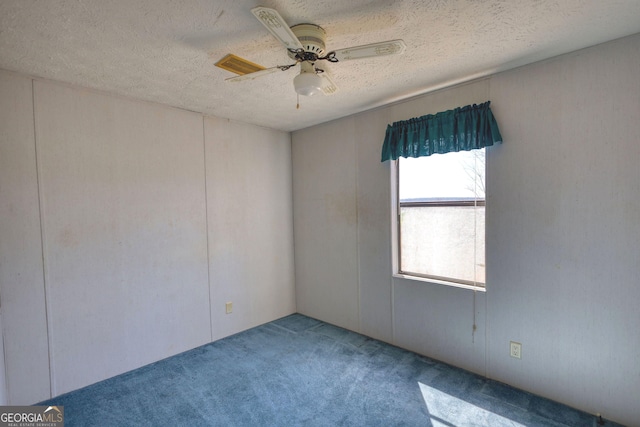 spare room featuring carpet flooring, visible vents, a textured ceiling, and a ceiling fan