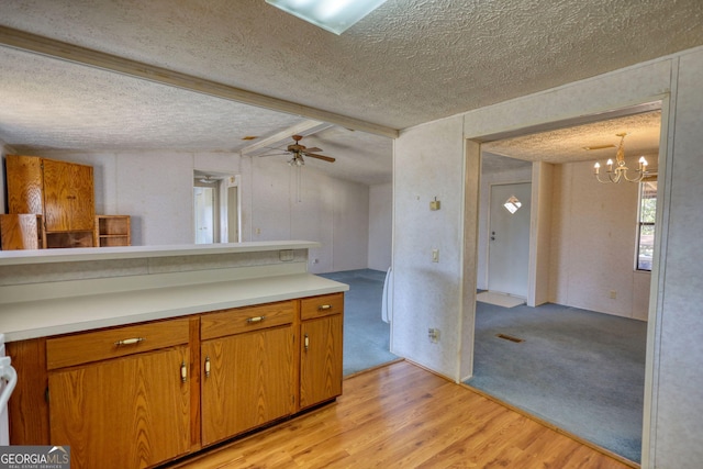 kitchen with light wood-style flooring, a textured ceiling, light countertops, and brown cabinets