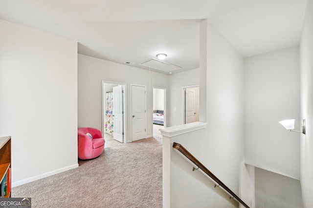 corridor featuring visible vents, baseboards, light colored carpet, attic access, and an upstairs landing