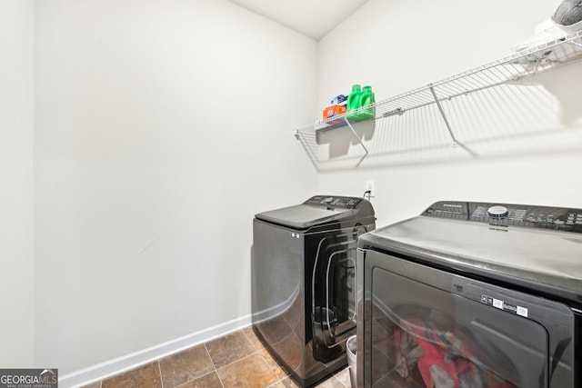 clothes washing area featuring washing machine and clothes dryer, laundry area, and baseboards