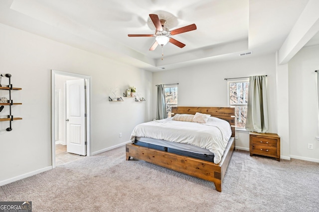 bedroom featuring visible vents, a raised ceiling, multiple windows, and carpet floors