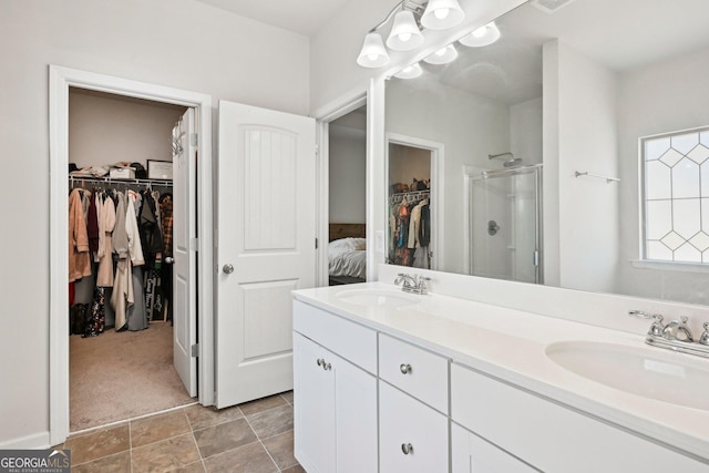 full bathroom with a sink, a walk in closet, double vanity, and a shower stall