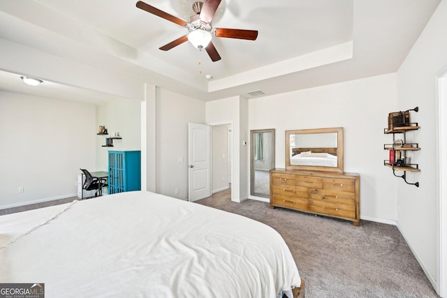 carpeted bedroom featuring a raised ceiling, baseboards, visible vents, and ceiling fan