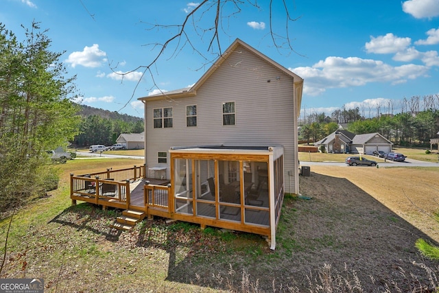 back of property featuring a wooden deck, a lawn, and a sunroom