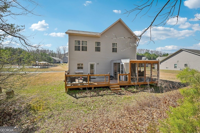 back of property featuring a yard, a sunroom, and a wooden deck