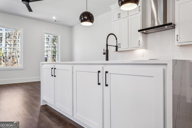 kitchen with decorative light fixtures, backsplash, white cabinetry, wall chimney exhaust hood, and dark wood-style flooring