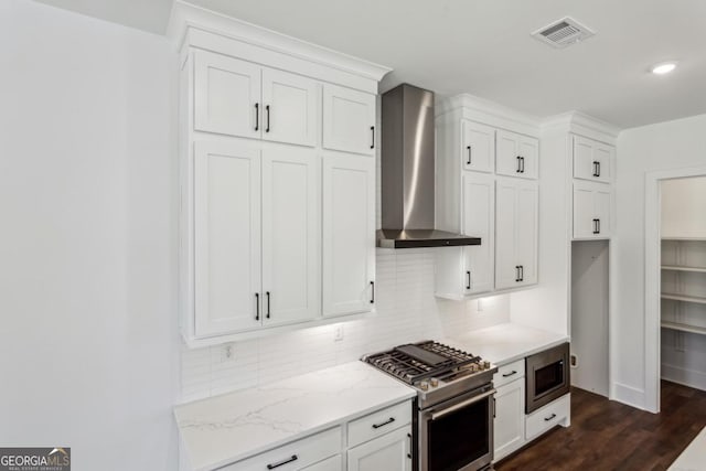 kitchen featuring tasteful backsplash, wall chimney exhaust hood, visible vents, and stainless steel appliances