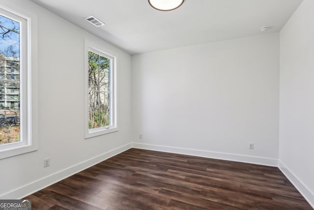 spare room with visible vents, baseboards, and dark wood finished floors