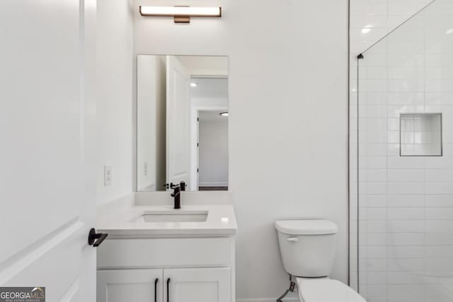 full bath featuring vanity, toilet, and a tile shower