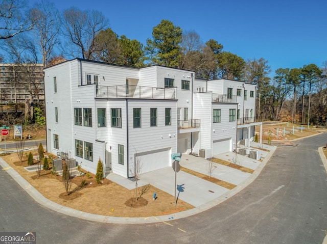 multi unit property with central AC, a balcony, concrete driveway, and a garage