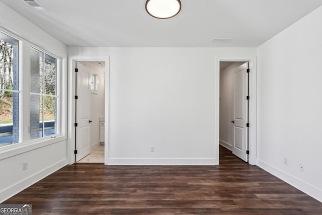 unfurnished room featuring visible vents, wood finished floors, and baseboards