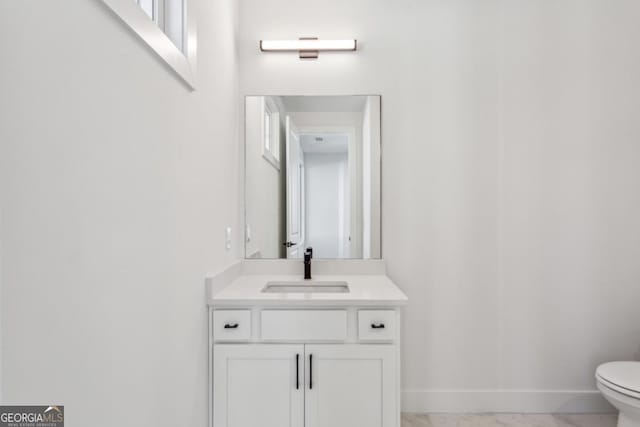 bathroom with baseboards, toilet, marble finish floor, and vanity